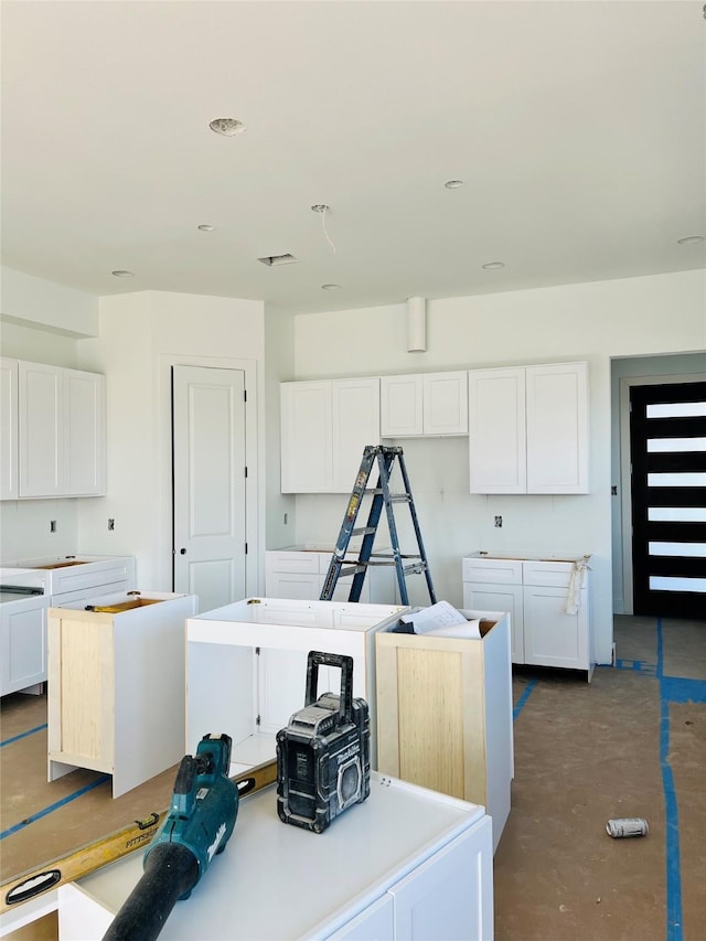 kitchen with a kitchen island, white cabinets, and concrete floors