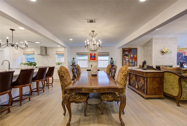 dining room with an inviting chandelier, sink, light hardwood / wood-style floors, and a textured ceiling