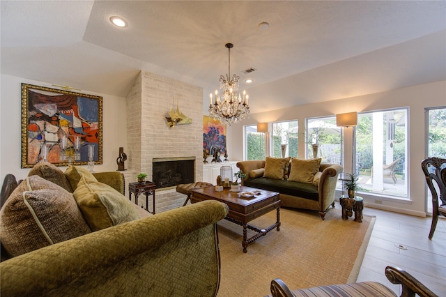 living room with light hardwood / wood-style flooring, a fireplace, vaulted ceiling, and an inviting chandelier