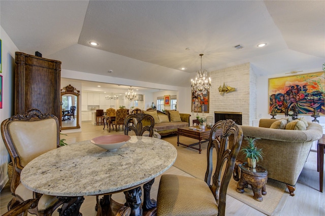 dining space featuring vaulted ceiling, a healthy amount of sunlight, a fireplace, and a chandelier