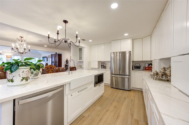 kitchen featuring sink, hanging light fixtures, white cabinets, and appliances with stainless steel finishes