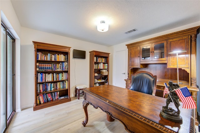 office with a textured ceiling and light wood-type flooring