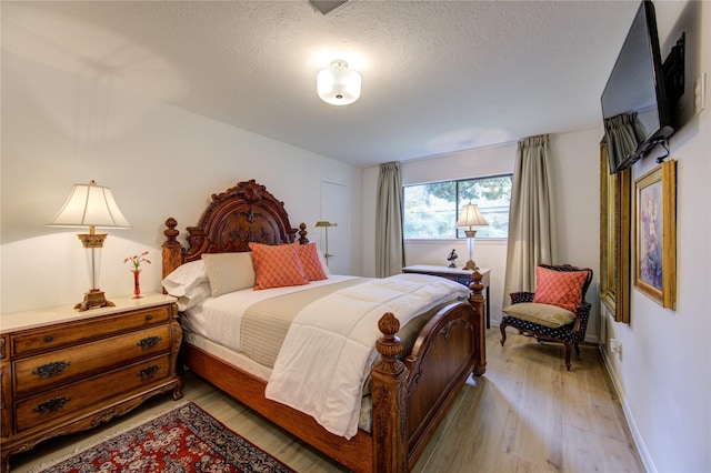 bedroom featuring a textured ceiling and light hardwood / wood-style flooring