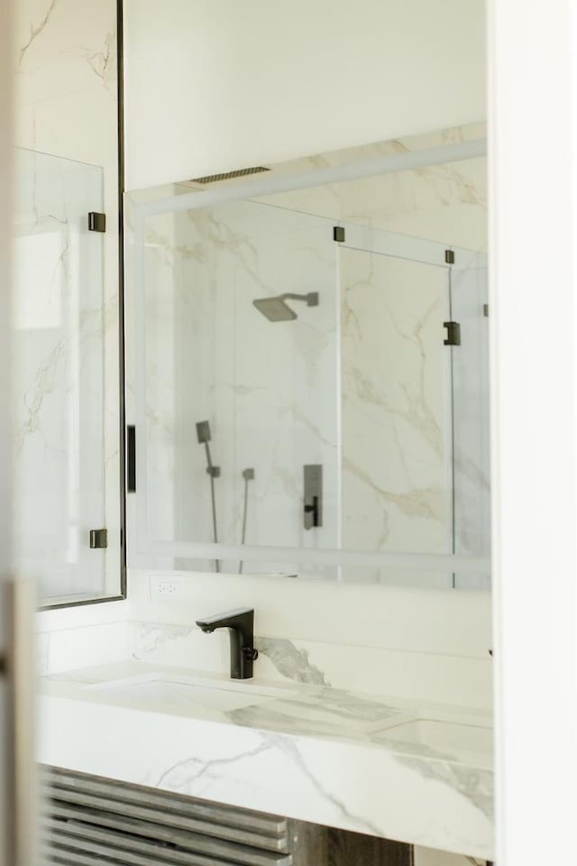 bathroom with vanity and a marble finish shower