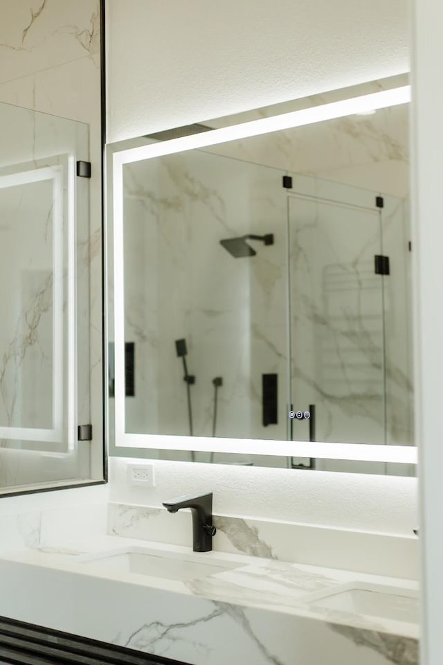 bathroom featuring a marble finish shower and vanity