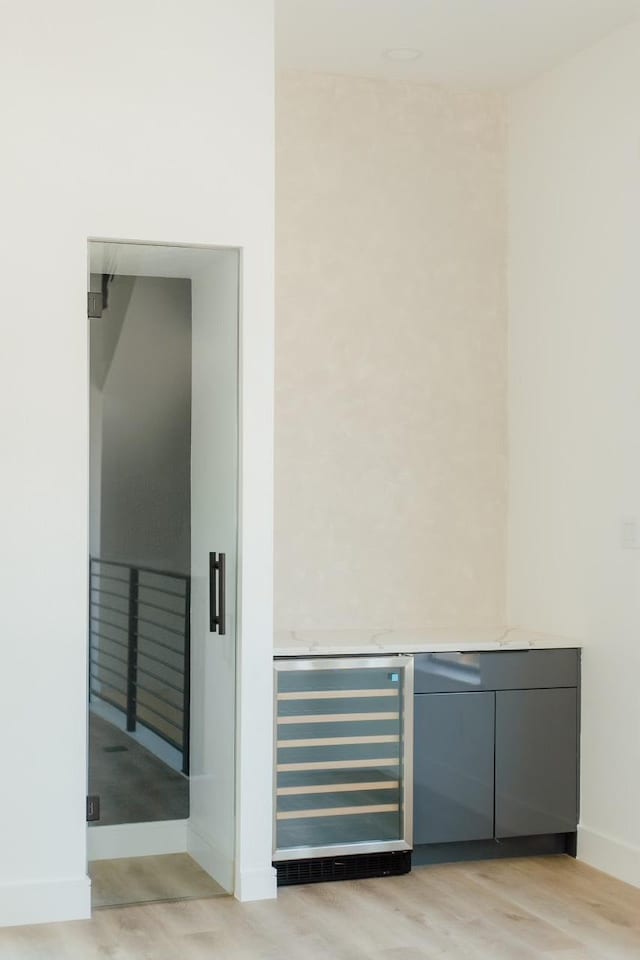 interior space with light wood-type flooring, beverage cooler, and baseboards