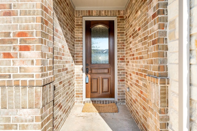 view of exterior entry featuring brick siding