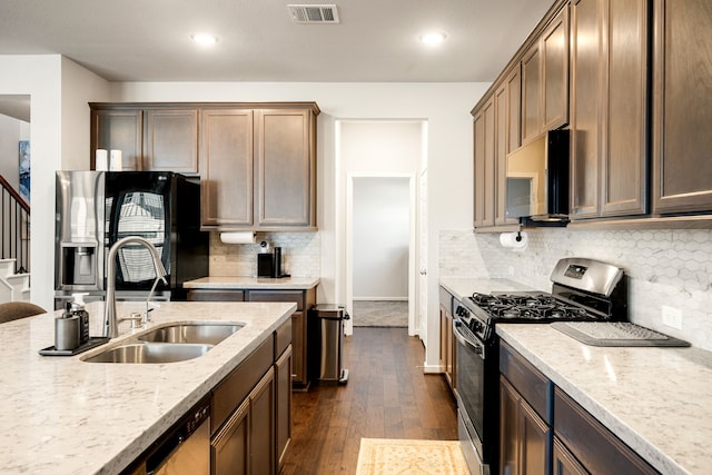 kitchen with dark wood finished floors, stainless steel appliances, visible vents, a sink, and light stone countertops