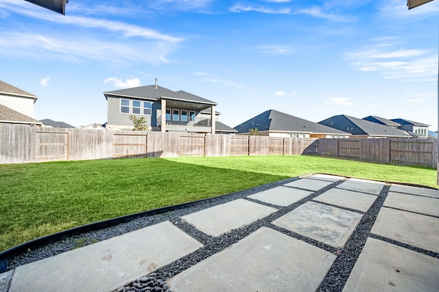 view of yard with a patio area, a fenced backyard, and a residential view