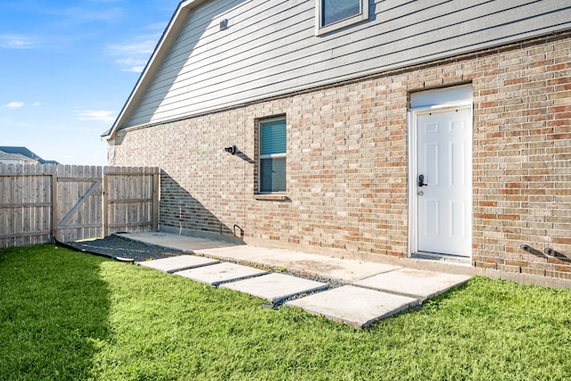 rear view of property featuring a yard, brick siding, and fence