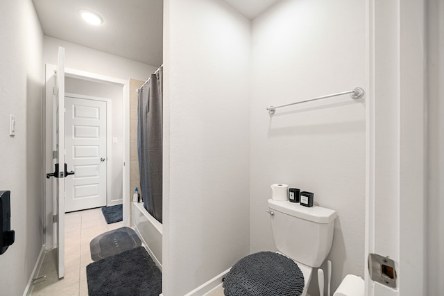 bathroom with toilet, tile patterned flooring, baseboards, and shower / bath combo with shower curtain