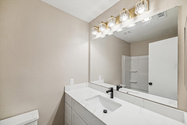 bathroom featuring walk in shower, vanity, and toilet