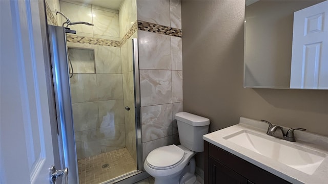 bathroom featuring vanity, a shower with shower door, and toilet