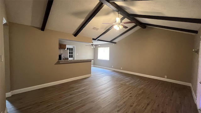 unfurnished living room with dark wood-type flooring, ceiling fan, a textured ceiling, and vaulted ceiling with beams