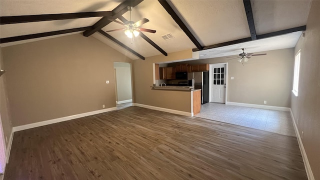 unfurnished living room with ceiling fan, dark hardwood / wood-style floors, and vaulted ceiling with beams