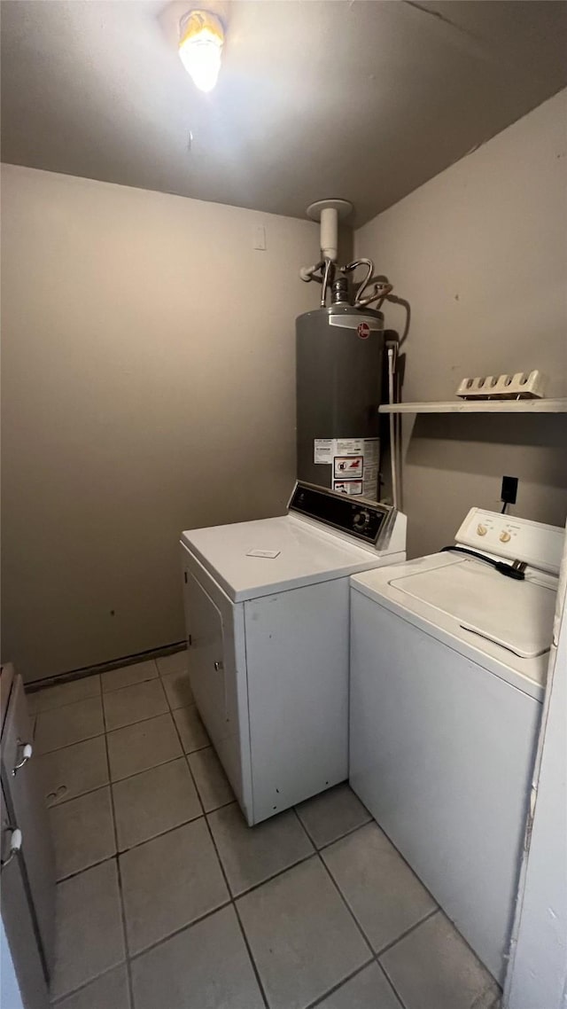 washroom with gas water heater, washer and dryer, and light tile patterned flooring