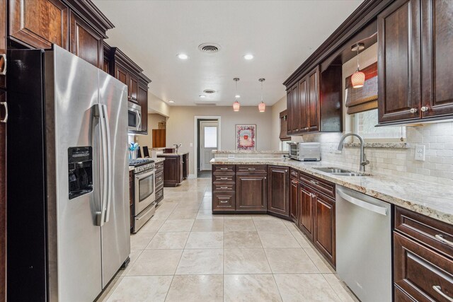 kitchen featuring appliances with stainless steel finishes, pendant lighting, tasteful backsplash, sink, and light tile patterned floors