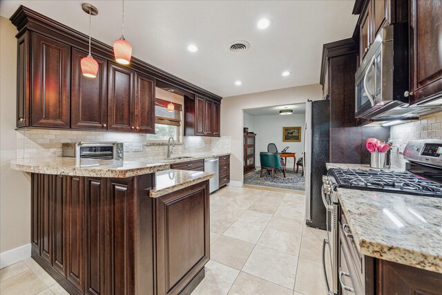 kitchen with light stone counters, hanging light fixtures, sink, and appliances with stainless steel finishes