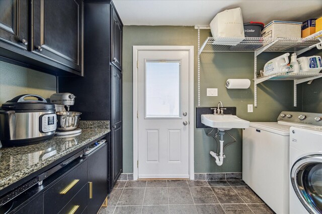 washroom featuring cabinets, sink, washing machine and clothes dryer, and dark tile patterned floors