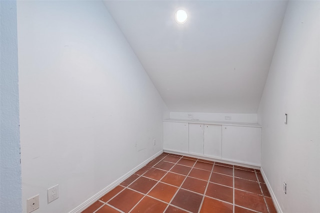 additional living space with lofted ceiling and dark tile patterned flooring