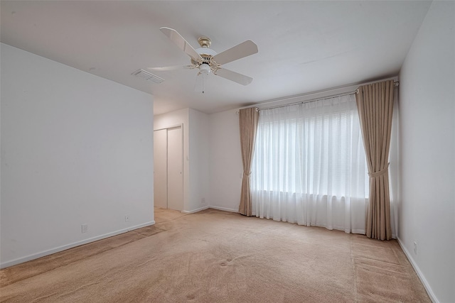 unfurnished room with light colored carpet and ceiling fan