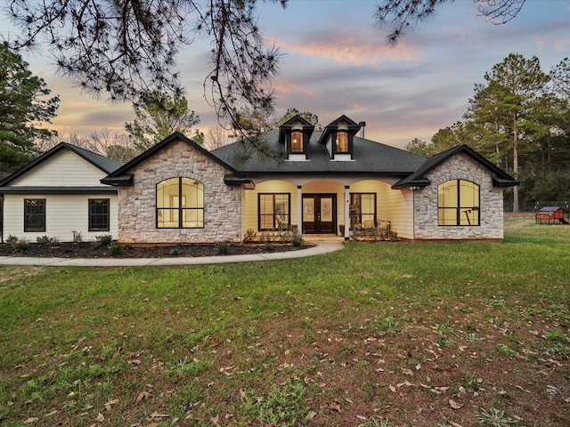 french country home with french doors, a yard, and covered porch