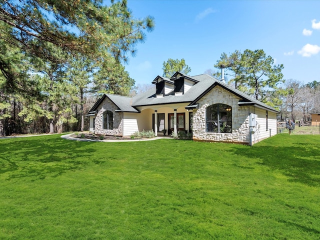 back of house with stone siding and a lawn