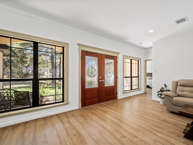 entrance foyer featuring visible vents, baseboards, light wood-style floors, and crown molding