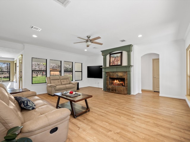 living room with light wood-type flooring, visible vents, and a tiled fireplace