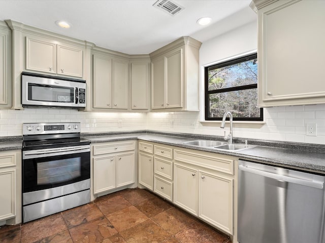 kitchen with visible vents, appliances with stainless steel finishes, cream cabinets, and a sink