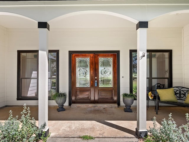 view of exterior entry with a porch and french doors