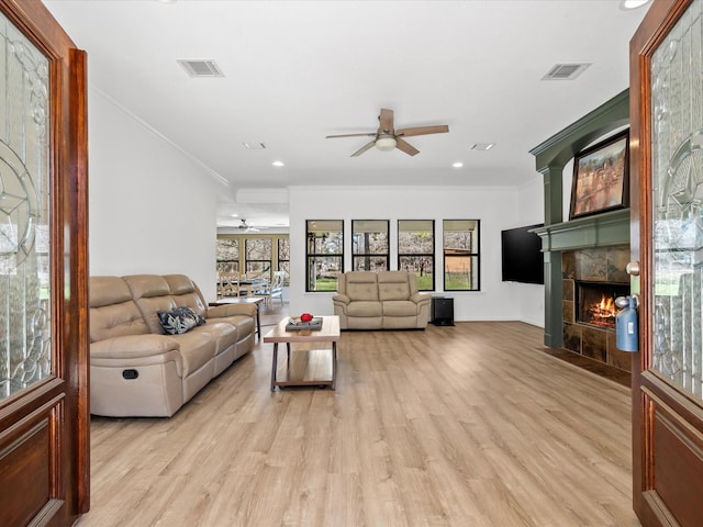 living area featuring a fireplace with flush hearth, light wood-type flooring, and visible vents