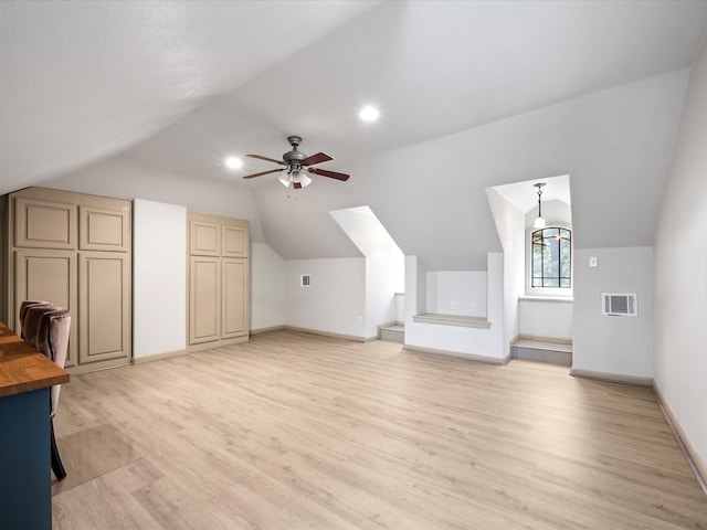 additional living space featuring light wood finished floors, visible vents, baseboards, ceiling fan, and lofted ceiling