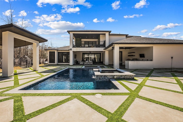 back of property featuring an outdoor kitchen, a balcony, a swimming pool with hot tub, and a patio