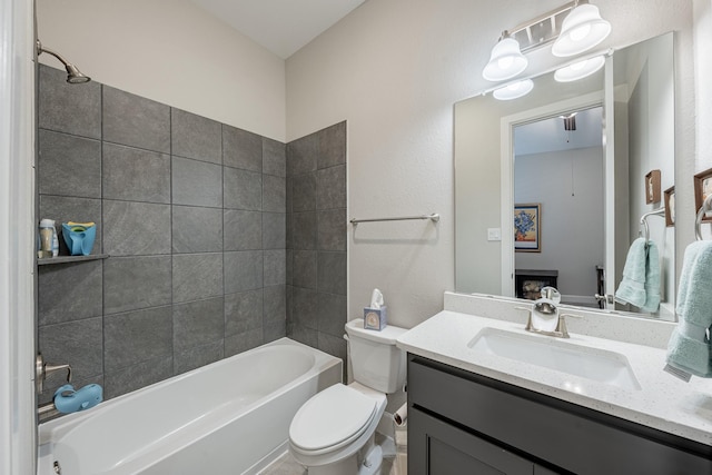 full bathroom featuring tiled shower / bath, vanity, and toilet