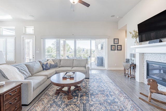 living room with ceiling fan, hardwood / wood-style floors, and a tile fireplace