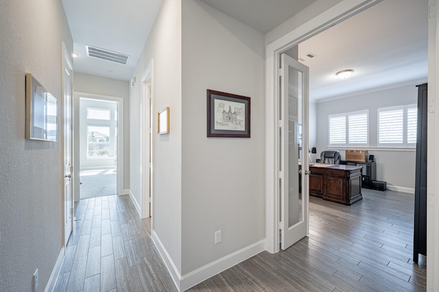 hall with hardwood / wood-style floors, a wealth of natural light, and ornamental molding