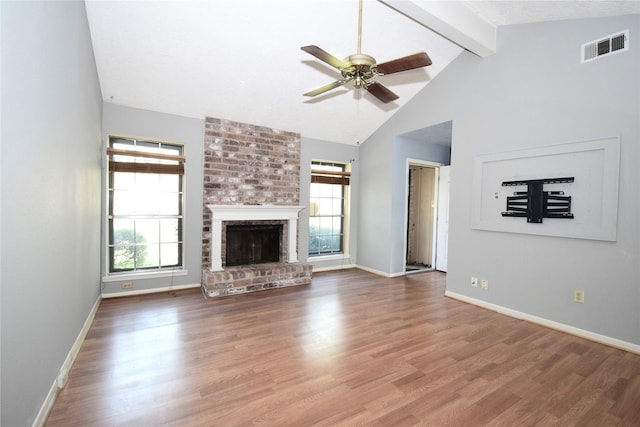 unfurnished living room with plenty of natural light, wood-type flooring, a brick fireplace, and vaulted ceiling with beams