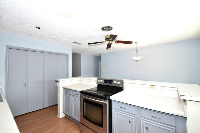 kitchen featuring gray cabinets, wood-type flooring, stainless steel range with electric stovetop, hanging light fixtures, and a textured ceiling