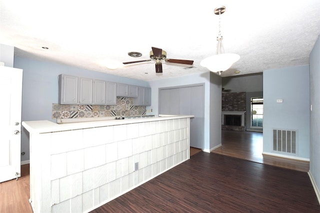 kitchen featuring gray cabinetry, decorative light fixtures, tasteful backsplash, and dark hardwood / wood-style floors