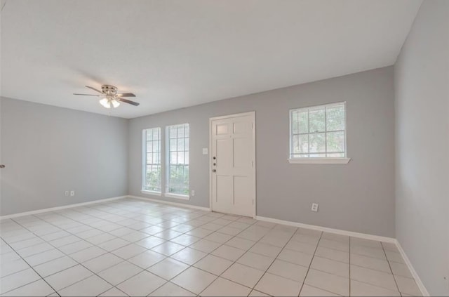 spare room featuring a healthy amount of sunlight, light tile patterned floors, and ceiling fan