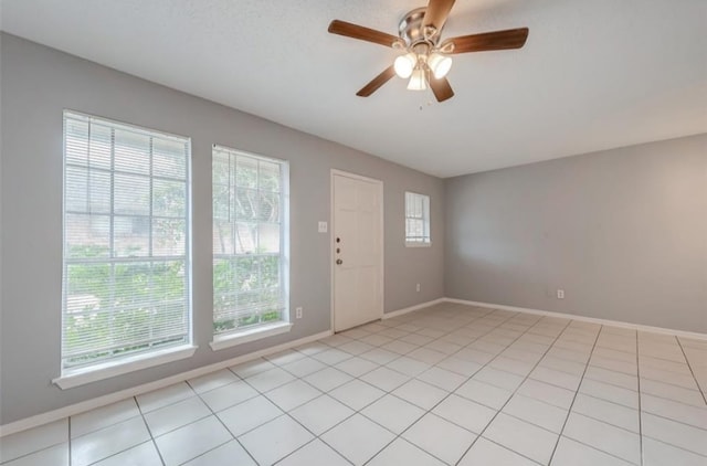 tiled empty room featuring ceiling fan