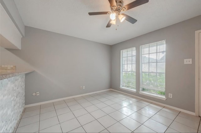 unfurnished room with ceiling fan, a textured ceiling, and light tile patterned floors