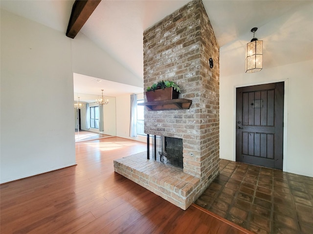 unfurnished living room featuring lofted ceiling with beams, a brick fireplace, dark hardwood / wood-style floors, and a chandelier