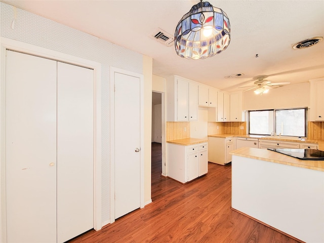 kitchen with white cabinetry, decorative backsplash, hardwood / wood-style flooring, hanging light fixtures, and ceiling fan