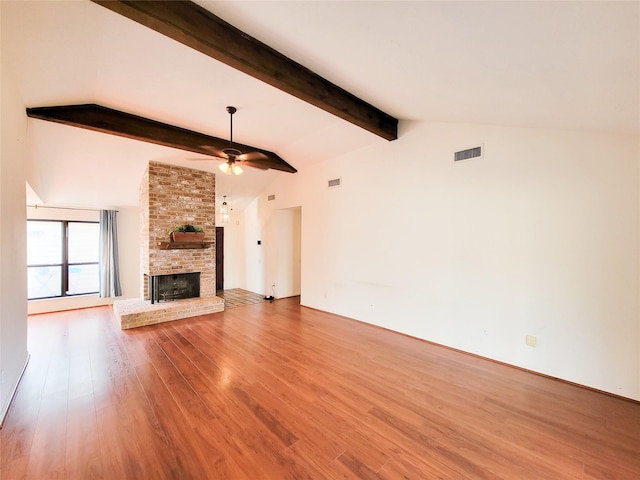 unfurnished living room with lofted ceiling with beams, a brick fireplace, light wood-type flooring, and ceiling fan