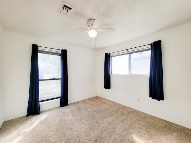 empty room featuring light carpet, ceiling fan, and a textured ceiling