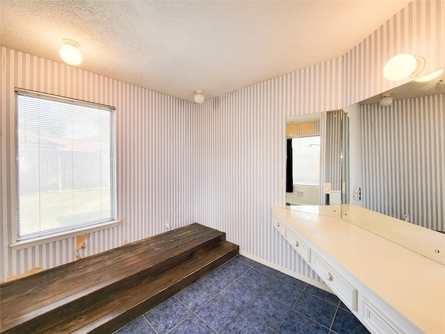 mudroom with dark tile patterned flooring and a textured ceiling