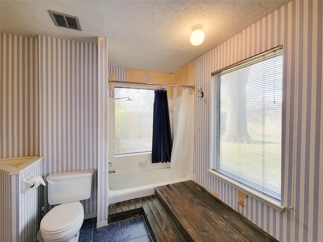 bathroom featuring tile patterned flooring, a textured ceiling, shower / bath combo, and toilet