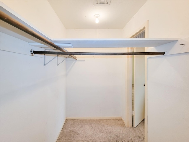 walk in closet with light carpet